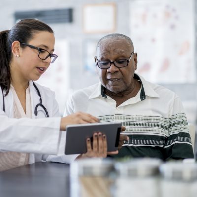 An older man and a doctor looking at a tablet.