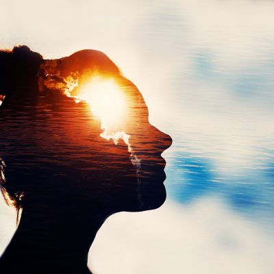 A silhouette of a woman's head with the sun behind it.