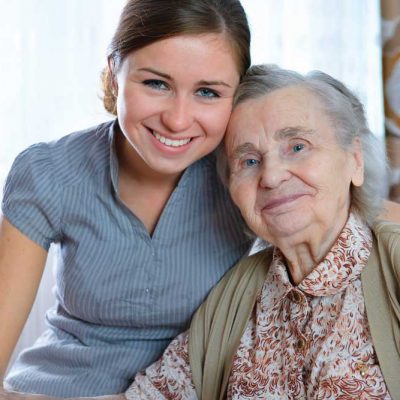 A woman is posing for a photo with an elderly woman.
