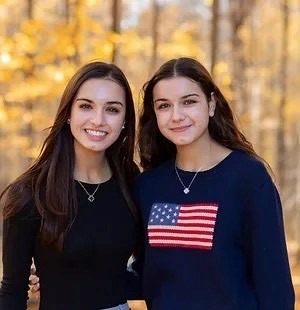 Two girls posing for a photo in the woods.