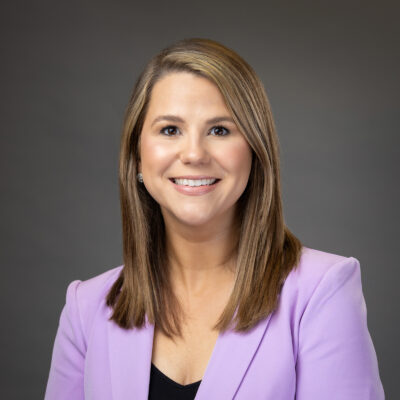 Professional headshot of a smiling woman wearing a lavender blazer.