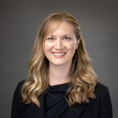 Professional woman smiling against a grey background.