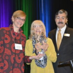 CMHA Lifetime Achievement Award Recipient Gail Lanphear Three people standing in front of a podium with an award.