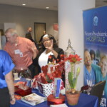 People interacting at a booth with a NeuroPsychiatric Hospitals banner and various promotional materials on a table.