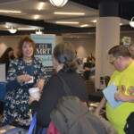 People interacting at a conference booth with promotional materials and banners around.