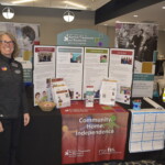 A woman stands beside a display booth for the Center for Autism Treatment and Research, featuring informational panels and brochures, at a community event.